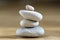 Group of zen stones pile, grey meditation pebbles tower on light brown wooden background in sunlight