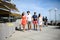 Groupe of young people man and woman walking on seaside of touristic resort during sunny summer day