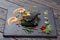 Grouper`s grilled fillet on a spinach bed. Fish on the black slate, shale board. Lemon pieces, sauce and rosemary