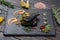 Grouper`s grilled fillet on a spinach bed. Fish on the black slate, shale board. Lemon pieces, sauce and rosemary