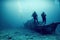 Groups of scuba divers and divers underwater view on the background of sunken wreckage.