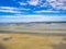 Groups of tourists walking on the colourful sand flats surrounding Le Mont Saint Michel during low tide, Normandy, Northern France