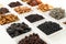 Groups of various kinds of dried fruits in square white bowls on white background