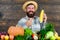 Grow organic crops. Man cheerful bearded farmer hold corncob or maize wooden background. Farmer straw hat presenting