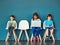 Growing up in a wireless world. Studio shot of kids sitting on chairs and using wireless technology against a blue