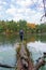 Grown man balancing on a log over the lake in autumn