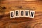 ` GROWN ` text made of wooden cube on  wooden background