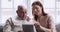 Grown up granddaughter teaching older grandpa using digital tablet