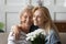 Grownup daughter greeting senior mother presenting flowers