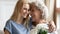 Grownup daughter hugs elderly mom congratulates her with 8-march