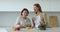 Grownup daughter and older mother talking, prepare salad in kitchen