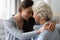 Grownup granddaughter touch foreheads hugs elderly grandmother enjoy tender moment