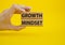 Growth Mindset symbol. Concept word Growth Mindset on wooden blocks. Beautiful yellow background. Businessman hand. Business and