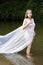 Growth portrait of a girl in a white dress standing in river