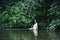 Growth portrait of a girl in a white dress standing in river