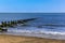 Groynes stretch out and submerging into the sea off Skegness beach, UK with a wind farm on the horizon