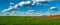 Grren wheat field near plowed hilly land at spring, sky with clouds