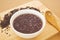 Gruel in white plastic bowl and wooden spoon on wooden cutting board