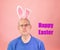 Grumpy old man with easter bunny ears looks deadpan at the camera