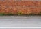 Grunge brick wall and a worn sidewalk with weeds. Asphalt road in front.  Background for copy space