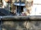 grunge deteriorating gray textured cracked stone balustrade with cafe patio terrace in the background