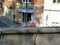 Grunge deteriorating gray textured cracked stone balustrade with cafe patio terrace in the background