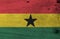 Grunge Ghanaian flag texture, horizontal triband of red, gold, and green with black star.