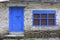 Grunge gray bricks wall with blue door and window of Nepal house