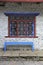 Grunge gray bricks wall with red windows and white curved steel, it is a side view of traditional Nepali house in countryside.