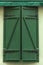 Grunge green wooden shutters with forged hinges.