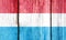 Grunge pattern of Luxembourg national flag isolated on weathered wooden fence board.