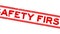 Grunge red safety first word square rubber stamp zoom on white background