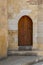 Grunge wooden aged vaulted door on exterior stone bricks wall