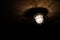 Grungy image with the light bulb and a metallic net on a worn out ceiling in an old prison cell