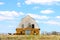 Grungy old stone barn surrounded by livestock in field with pretty blue sky with fluffy clouds