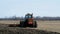 GRYGLA, MN - 02 NOV 2019: Red farm tractor pulling cultivator turning up black soil on field after harvest of soy beans.