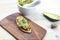 Guacamole on a baguette slice, rustic dÃ©cor with wood boards and a mortar and pestle