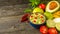 Guacamole in blue bowl on natural rustic desk with ingredient: lemon, tomatoes, peppers around.