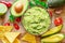 Guacamole, guacamole ingredients and chips on wooden background. Flat lay