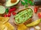 Guacamole, guacamole ingredients and chips on wooden background. Flat lay