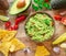 Guacamole, guacamole ingredients and chips on wooden background. Flat lay