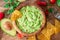 Guacamole, guacamole ingredients and chips on wooden background. Flat lay