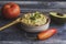 Guacamole sauce in a bowl with a wooden spoon, tomato, avocado, chili pepper on wooden background