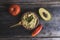 Guacamole sauce in a bowl with a wooden spoon, tomato, avocado, chili pepper on wooden background