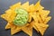 Guacamole sauce and tortilla chips, popular Mexican food, on slate serving board. Top view