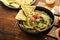 Guacamole. Traditional latinamerican Mexican dip sauce in a black bowl with avocado and ingredients and corn nachos. Avocado