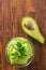 Guacamole on wooden table surrounded by its ingridients