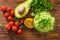 Guacamole on wooden table surrounded by its ingridients