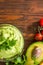 Guacamole on wooden table surrounded by its ingridients