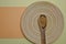 Guarana powder in a wooden spoon and a bamboo plate on a yellow-orange pastel background.